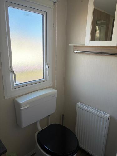 a bathroom with a toilet and a window at PG173 Golden Palm Resort 6 Berth Caravan With Decking in Chapel Saint Leonards