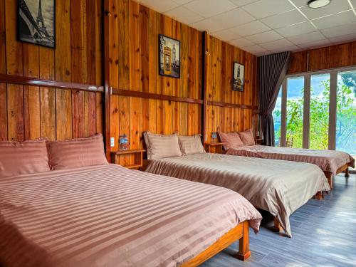 two beds in a room with wooden walls at Bungalow Scent in Da Lat