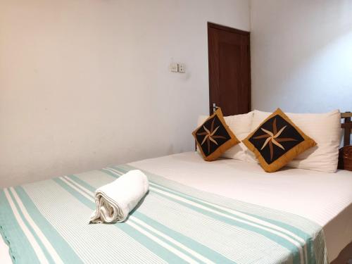a bedroom with a bed with a blanket and pillows at Green Shadow Inn in Galle
