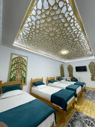 a room with four beds and a large window at Olimxon Guest House in Bukhara