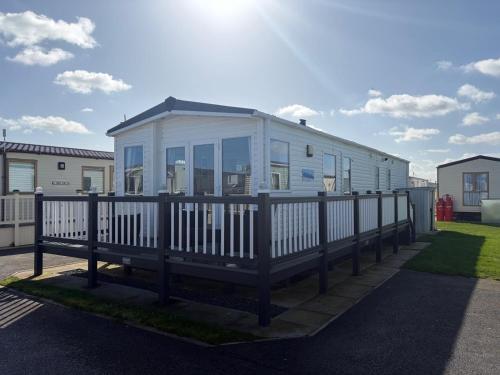 a mobile home with a wooden fence next to it at PG177 Golden Palm Resort 8 Berth Caravan With Decking in Chapel Saint Leonards
