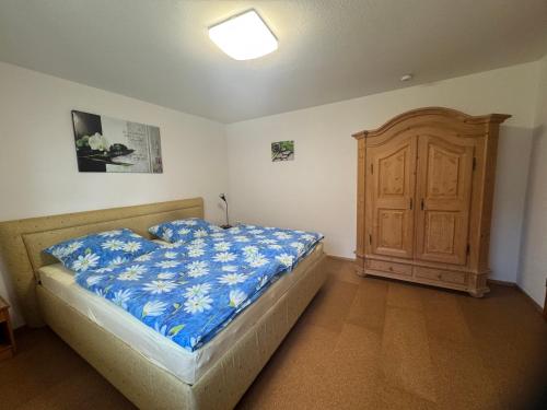 a bedroom with a bed with blue sheets and a wooden cabinet at Ferienwohnung Haus Veronika in Wegscheid