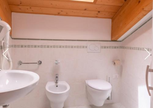 a white bathroom with a sink and a toilet at Hotel Merano in Misano Adriatico