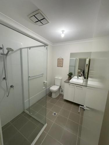 a bathroom with a shower and a toilet and a sink at Guest house Que Sera in Cooranbong