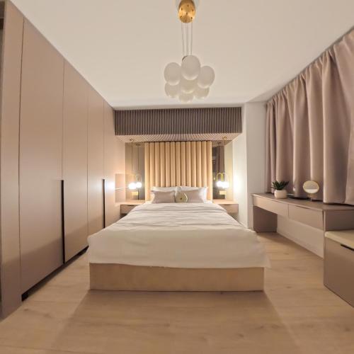 a bedroom with a large white bed and a chandelier at LUAME Residence , langa Arena Mall, aproape de centru in Bacău