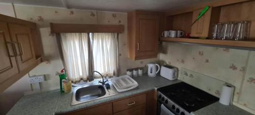 a small kitchen with a sink and a stove at Towyn Happy Days K3 in Rowen