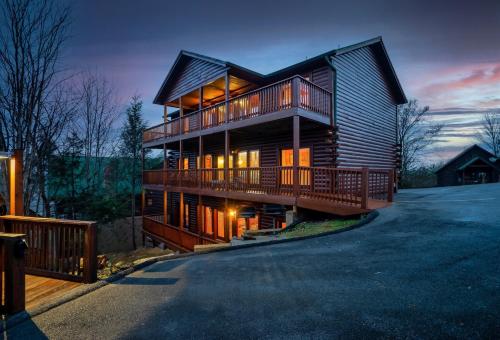 a log cabin with a deck and a house at Private Sauna Cabin Sleeps 34 Game Rooms in Pigeon Forge