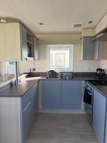 a kitchen with blue cabinets and a sink at PG177 Golden Palm Resort 8 Berth Caravan With Decking in Chapel Saint Leonards