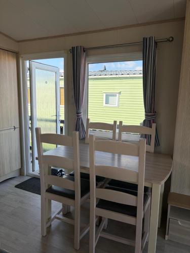 a dining room with a table and chairs and a window at PG177 Golden Palm Resort 8 Berth Caravan With Decking in Chapel Saint Leonards