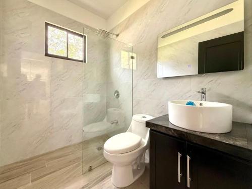 a bathroom with a toilet and a sink and a mirror at Coral Breeze in Puntarenas