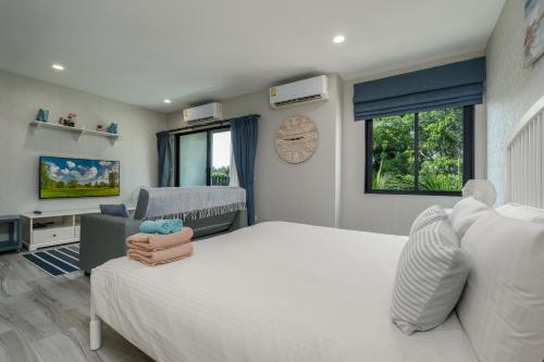 a bedroom with a large white bed and a clock at Cozy Studio Apartment E414 in Phuket