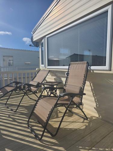 two chairs sitting on the deck of a house at PG69 Golden Palm 8 Berth Caravan with Decking in Chapel Saint Leonards