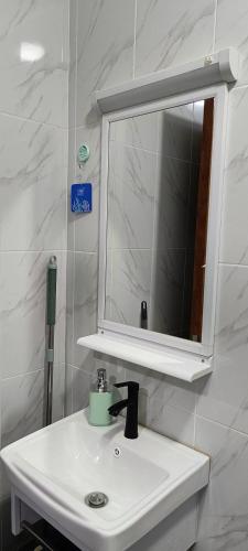 a bathroom with a white sink and a mirror at BlueByMis Studio Apartment in Muchatha