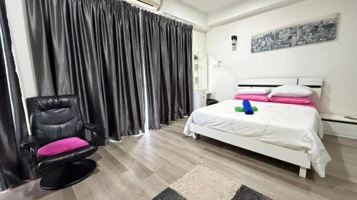 a bedroom with a white bed and a black chair at Aisyah Studio D perdana in Kota Bharu