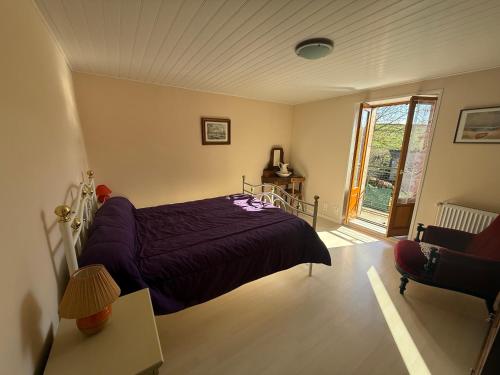 a bedroom with a bed with a purple bedspread at gite de Sauviat 25 chemin du grand Pacher le bourg de Sauviat 63120 in Sauviat