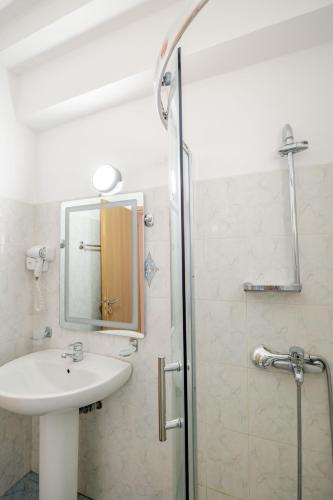 a bathroom with a sink and a shower with a mirror at The Eden Hotel in Sarandë