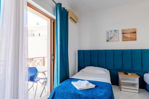 a bedroom with a blue bed and a balcony at The Eden Hotel in Sarandë