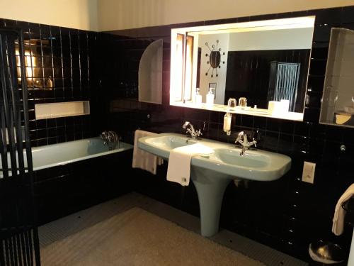 a bathroom with a sink and a mirror and a tub at Chambres d'Hôtes Maison La Porte Rouge in Niort