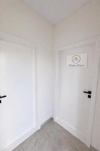 a white room with a door with a sign on it at Wake&wave in Užpelkiai