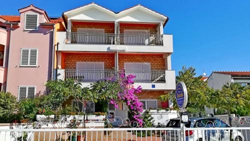 a pink apartment building with a balcony at Apartments Aurelia in Vodice