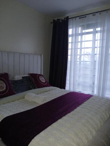 a bedroom with a large bed and a window at Beijing Nest in Syokimau