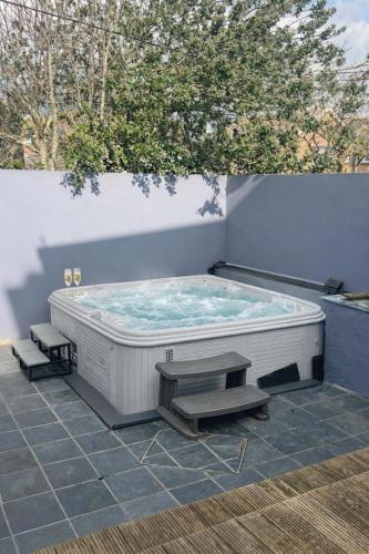 a hot tub on a patio with two benches at Beautiful 4 Bed Beach House in Pevensey