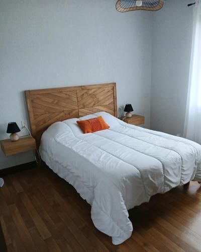 a bedroom with a large white bed with an orange pillow at Gîte rural indépendant in Barbaste
