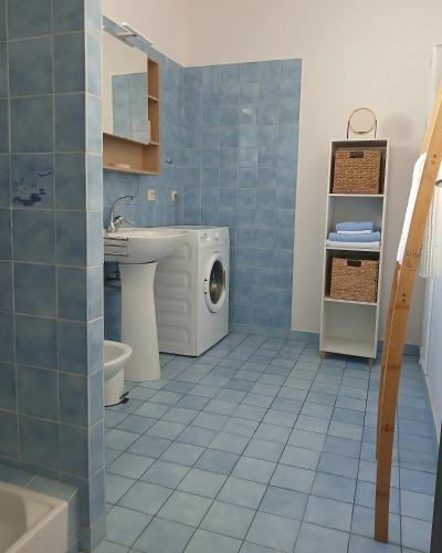 a blue tiled bathroom with a washing machine in it at Gîte rural indépendant in Barbaste