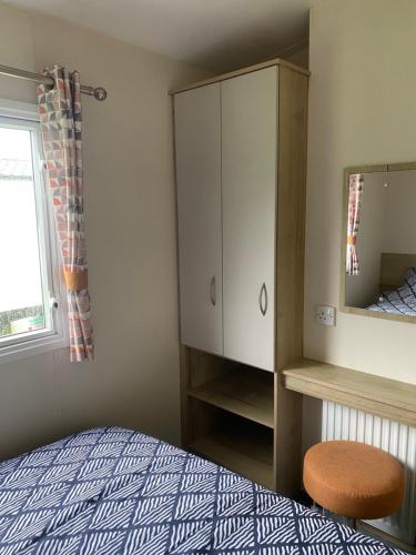a bedroom with a bed and a cabinet and a mirror at Caravan Holiday Park in Newquay in Newquay