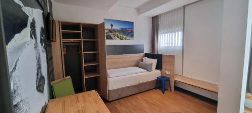 a small room with a bed and a book shelf at my MINGA Airport serviced Apartments in Hallbergmoos
