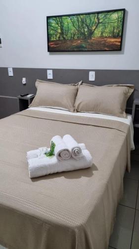 a bed with two towels and two rolled towels at Pousada Aconchego in Duas Estradas