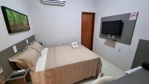 a bedroom with a bed with a tv on the wall at Pousada Aconchego in Duas Estradas