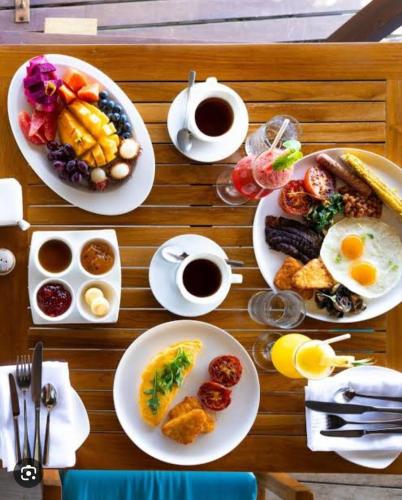 a table with plates of breakfast food and cups of coffee at Mannat Residency in Ghaziabad