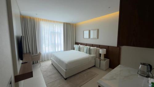 a bedroom with a white bed and a large window at Hatta Residence in Hatta
