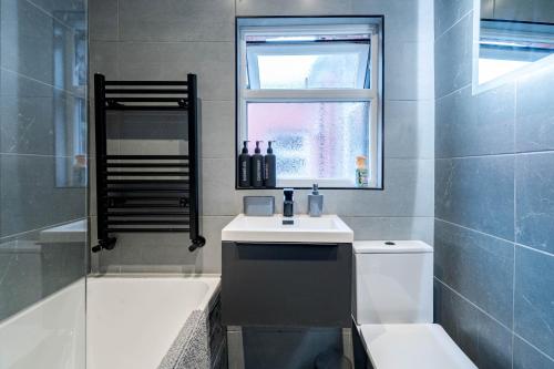 a bathroom with a sink and a toilet and a window at Spacious 3BR Stay - Free Parking - Near City Centre - Sleeps 6 in Manchester
