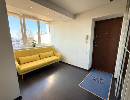 a living room with a yellow couch and a window at Birštonas Relax Apartment in Birštonas