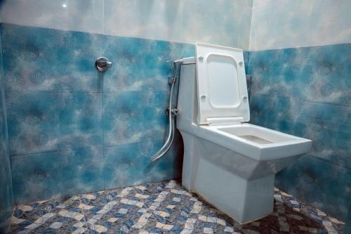 a bathroom with a toilet in a blue wall at Maneva Comforts in Mangalore
