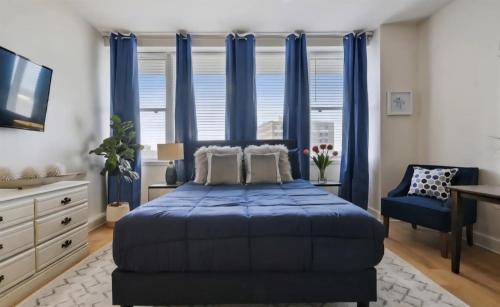 a bedroom with blue curtains and a bed and a desk at Beautiful Walk to French Quarter, Pool, Gym, View in New Orleans