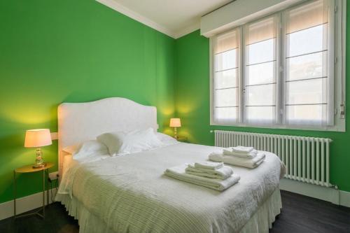 a green bedroom with a bed with towels on it at Green House Historic Centre in Bologna