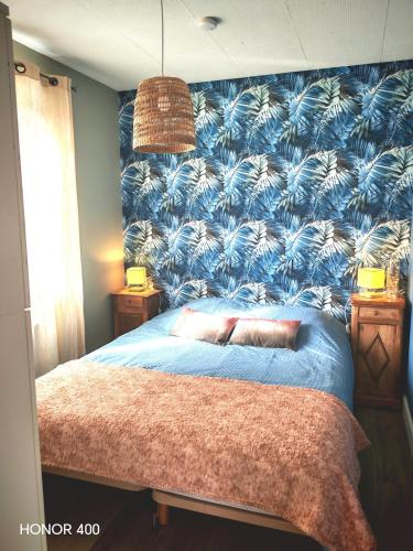 a bedroom with a blue wall with a large bed at Appartement à la Hume in Gujan-Mestras