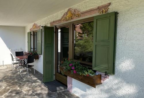 a building with green doors and a table with flowers at Chalet Villa Josi Superior Appartement 11 in Leutasch