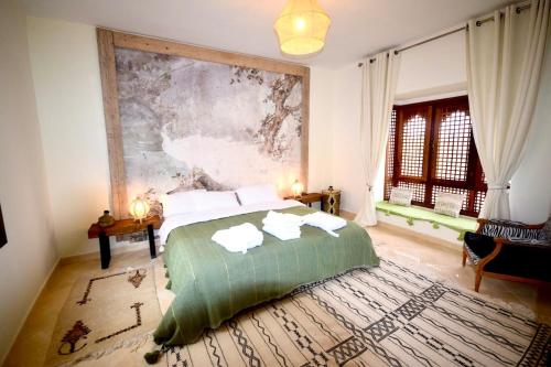 a bedroom with a bed and a large painting on the wall at Dar Alba in Marrakesh