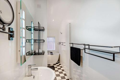 a white bathroom with a sink and a tub at Swan House in Southport