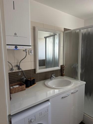 a white bathroom with a sink and a mirror at Apartment Perla in Dinjiška