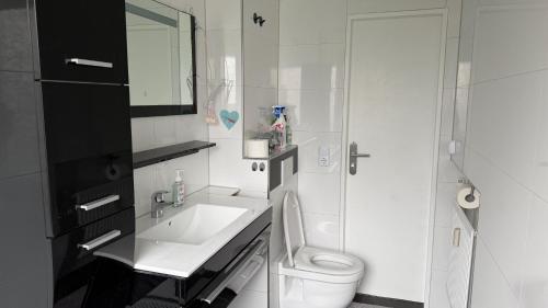 a white bathroom with a sink and a toilet at Ferienwohnung City in Nollingen