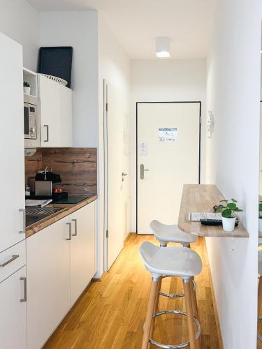 a kitchen with white cabinets and a table and stool at My Room Messe Munich Apartment in Munich