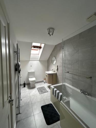 a bathroom with a tub and a toilet and a sink at Lilyscape At Whitehead in Whitehead