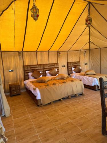 a bedroom with two beds in a tent at Achabou Desert Camp in Merzouga