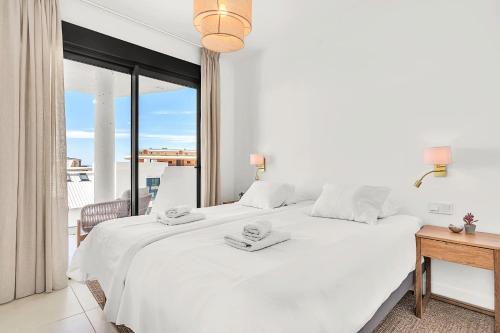 a white bedroom with a large bed and a balcony at Luxury Apartment Higueron in Fuengirola