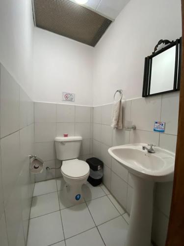 a white bathroom with a toilet and a sink at Mía Leticia B&B in Quito